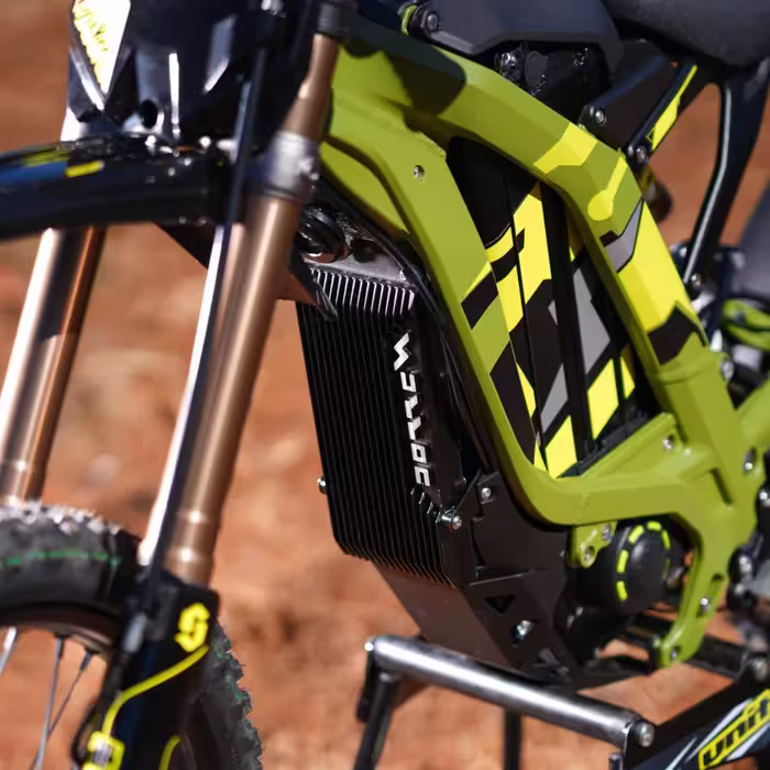 Close-up of the green and black electric dirt bike's front suspension, frame, and radiator.